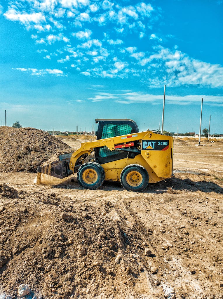 Skid steer loader at a daytime construction site with blue sky backdrop.