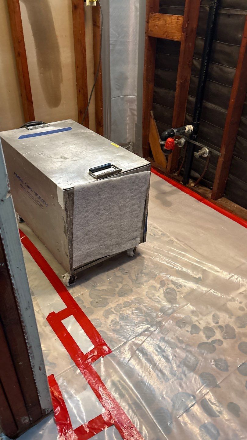 Air filtration equipment beside exposed framing and protected flooring in a Thousand Oaks asbestos work area